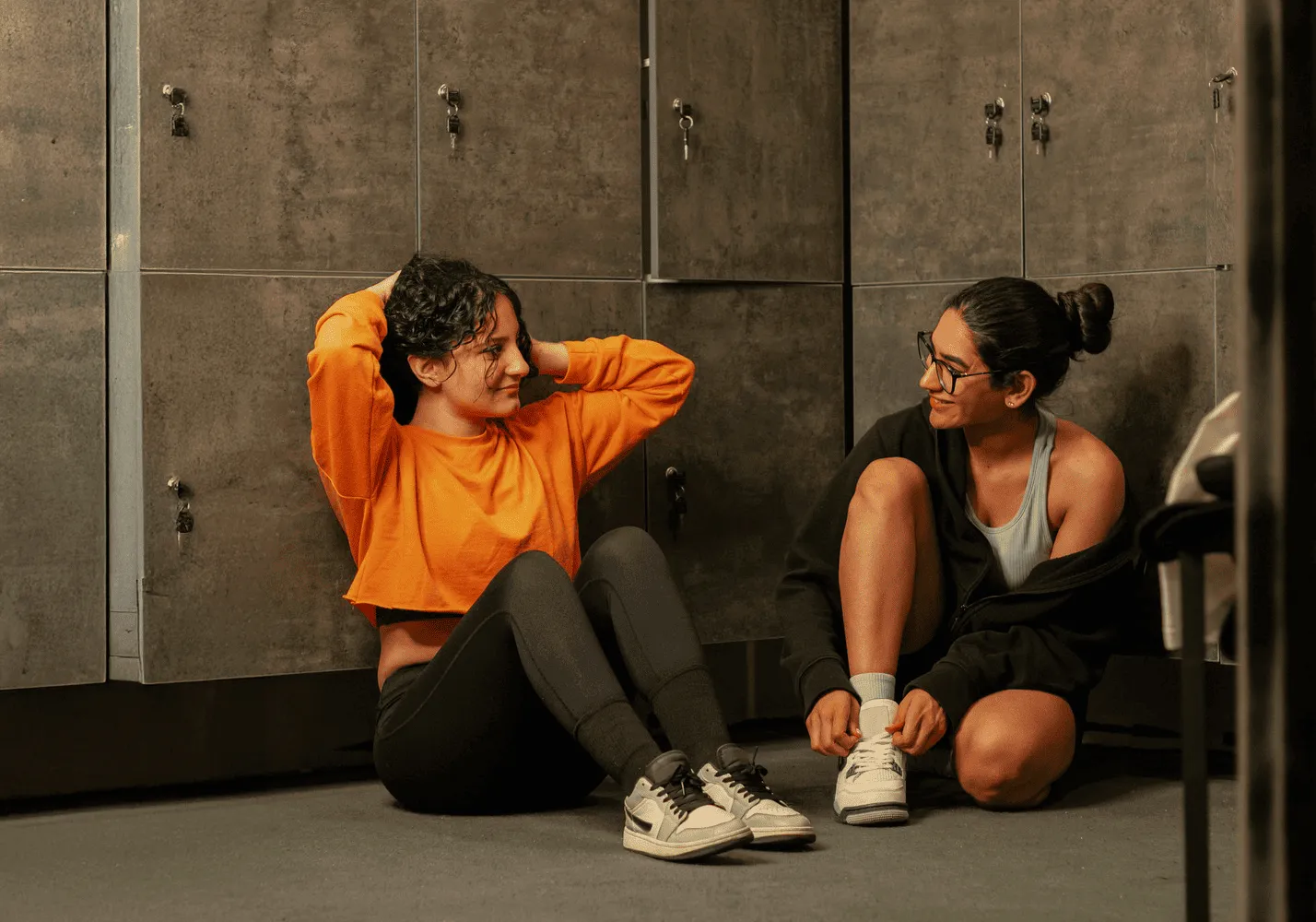 Dos personas charlando sentadas en el vestuario del gym